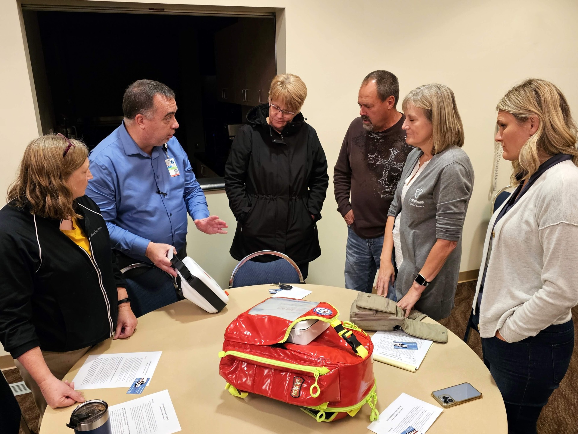 Residents gather around a table to learn more about Iowa United First Aid.